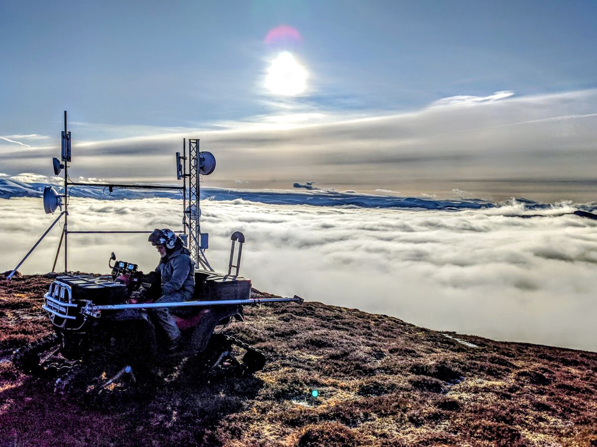 Engineer working at a Badenoch Broadband mast above the clouds in the Scottish Highlands